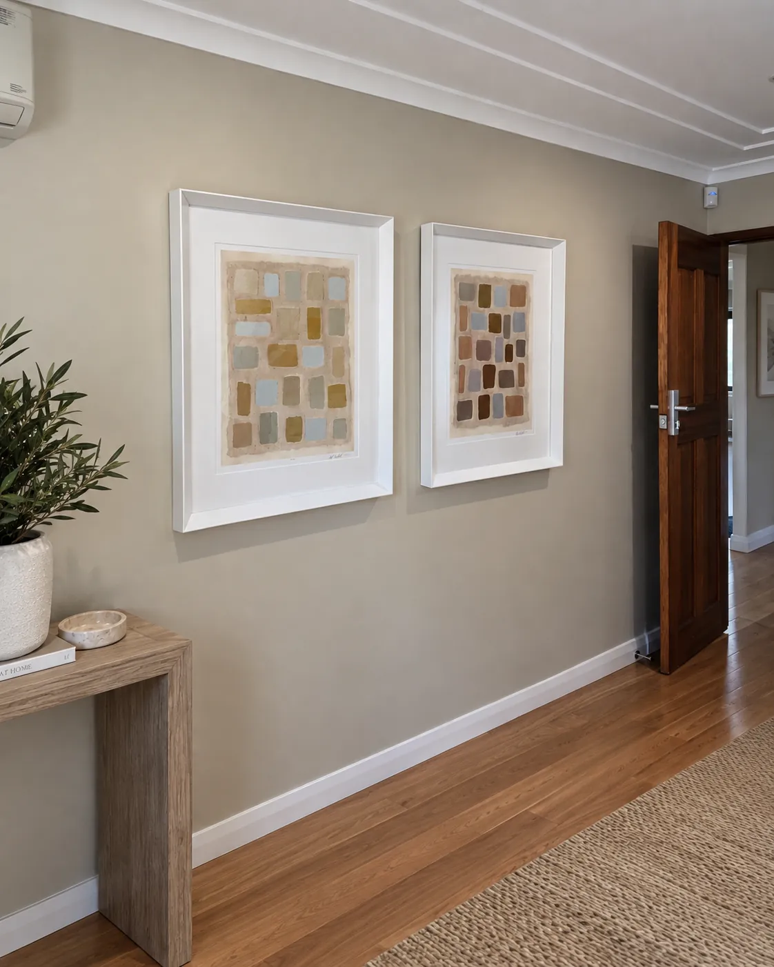 Two white-framed abstract artworks installed in a hallway
