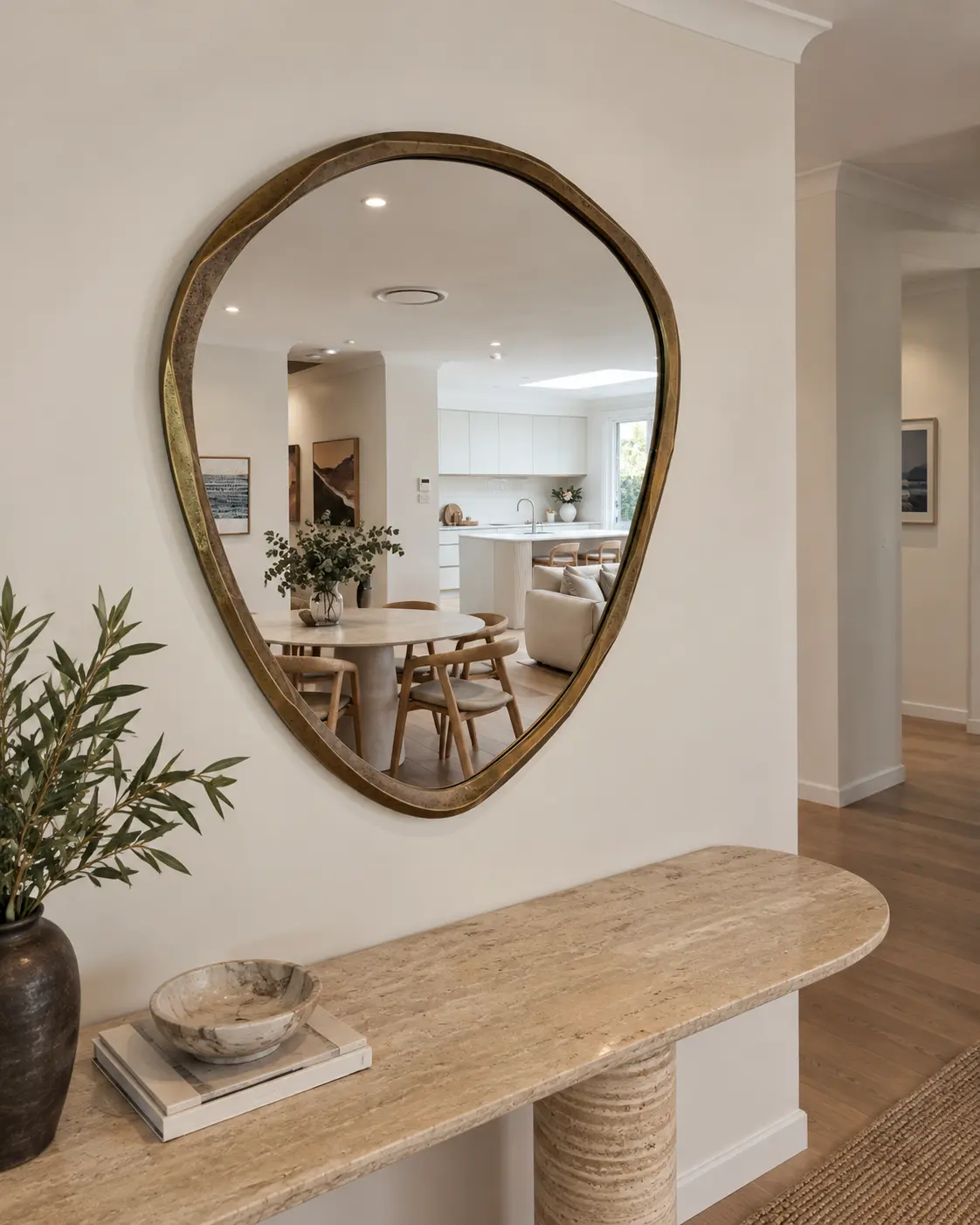 Organic brass mirror installed above an entry console