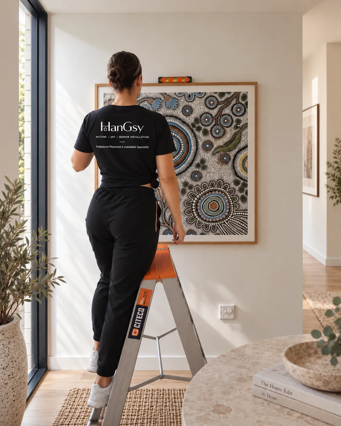 HanGsy installer positioning a large framed artwork in a hallway