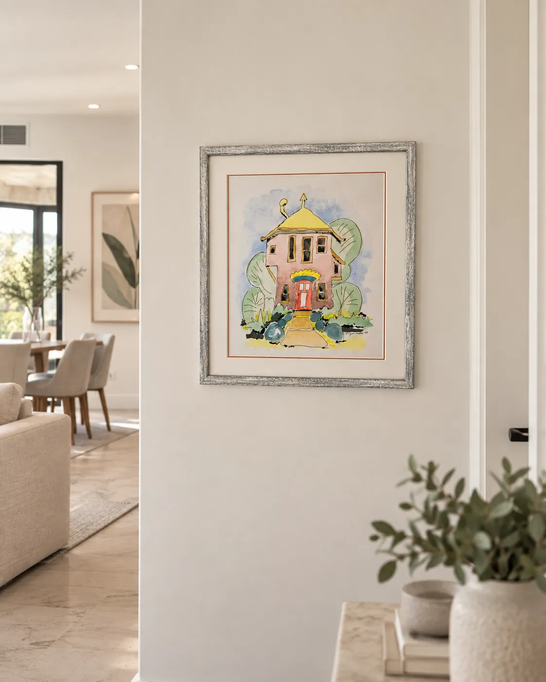 Framed artwork installed on a hallway wall beside a dining room