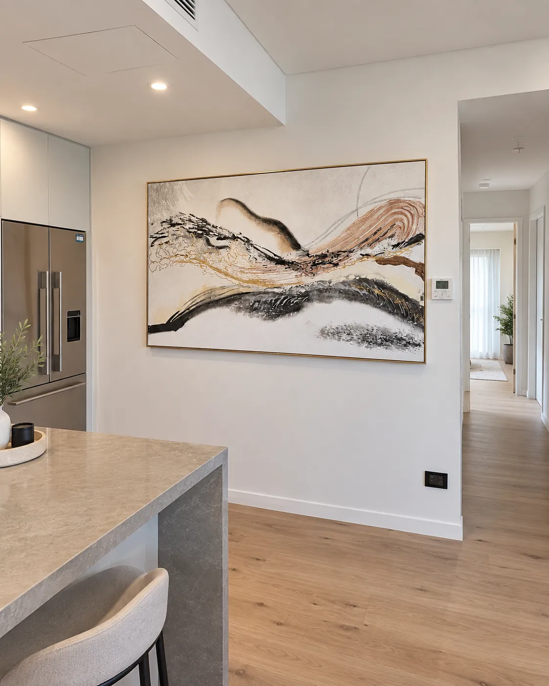 Wide gold-framed abstract canvas installed beside a kitchen bench