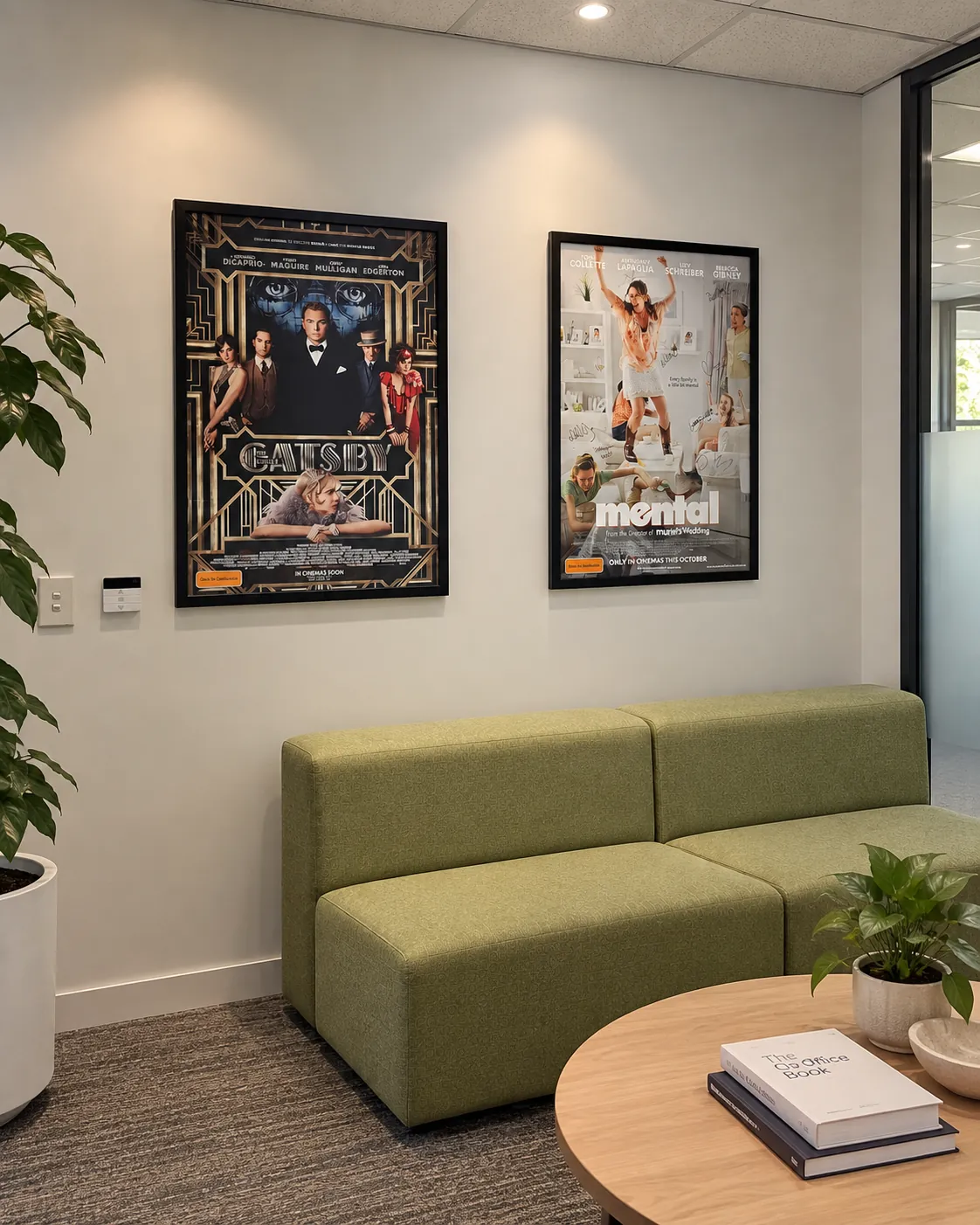 Two framed film posters installed above lounge seating in an office waiting area